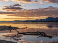 Wolkenleuchten über den Bergen hinter dem Chiemsee zum Sonnenaufgang